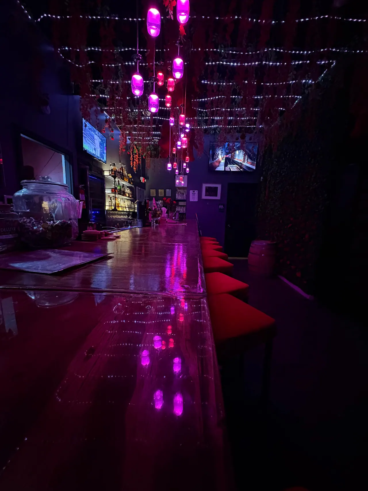 Intertwine's wooden bar and red stools beneath purple pendant lights