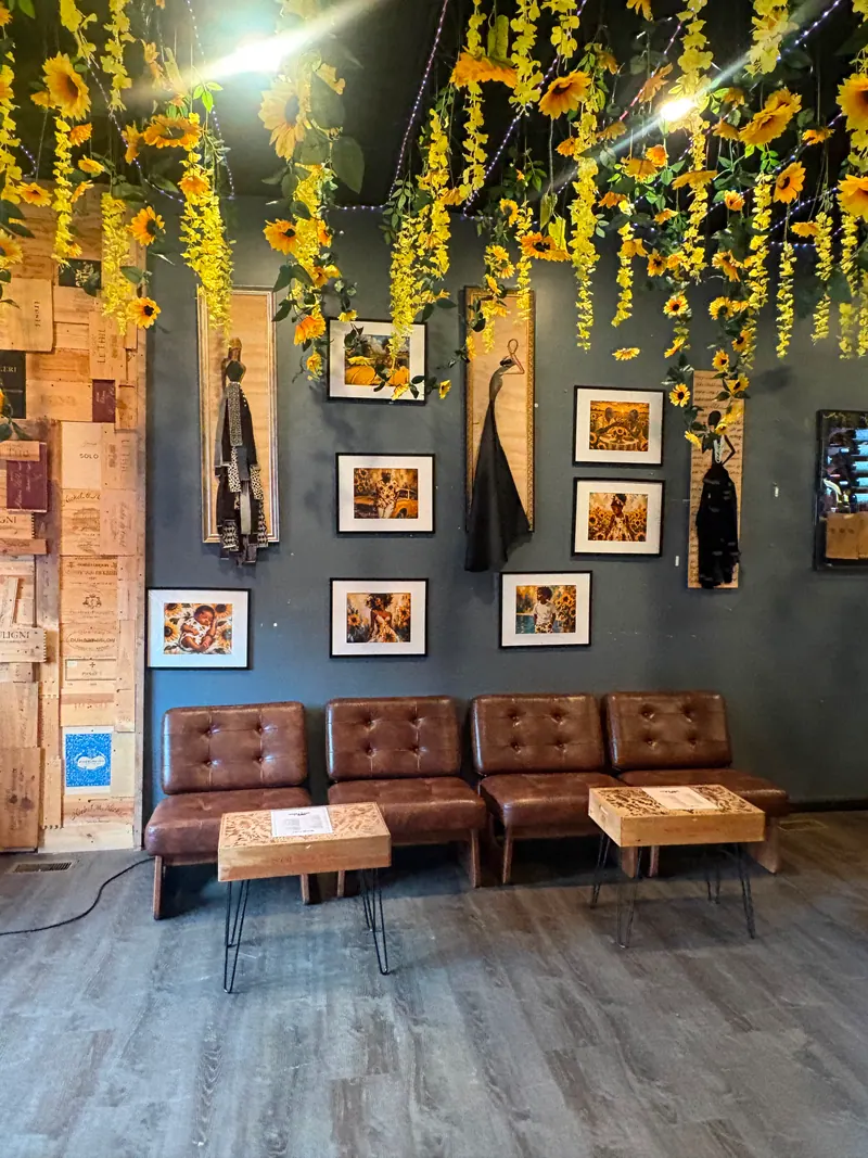 Framed artwork and leather seating beneath hanging sunflowers